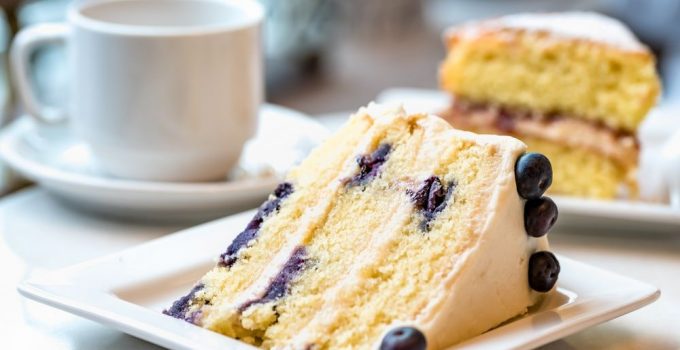 Three layered cake that is low carb with white icing and blueberries